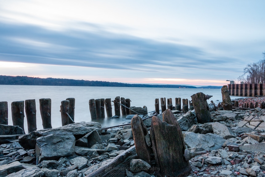 A photo of the old wood pilings along the shore of the Hudson River at Charles Rider Park during sunrise.