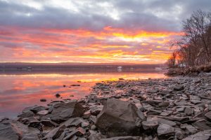 Orange clouds reflected on the Hudson River at Esopus Meadows Preserve during a January sunrise.