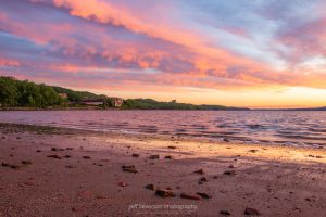 A photo of sunrise over the Hudson River along the brick-strewn beach at Kingston Point.