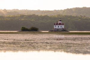 A photo of the Esopus Lighthouse on a lightly mist covered Hudson River during the golden hour of sunrise.