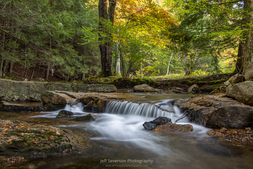 A photo of a small waterfall on the Coxing Kill at Mohonk Preserve on an autumn morning.