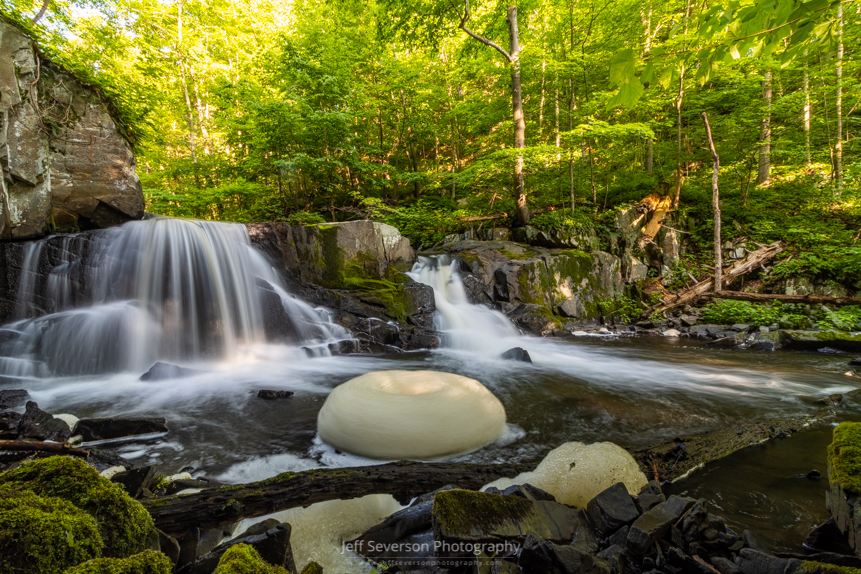 A long exposure photo of the Middle Falls waterfall and a giant spinning foam bubble on Black Creek in West Park, NY.