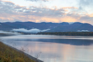 Morning light reflected off of a foggy lower basin of the Ashokan Reservoir before the sun crests the horizon.