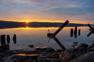 Remnants of an old pier along the Hudson River silhouetted as the sun breaks the horizon across from Charles Rider Park.