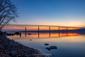 An April sunrise silhouetting the Kingston-Rhinecliff Bridge from along the shore of the Hudson River at Charles Rider Park in Kingston, NY.