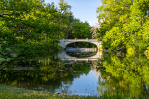 A photo of the White Bridge at the entranceway of the Vanderbilt Mansion National Historic Site reflected in Crum Elbow Creek on a May evening.
