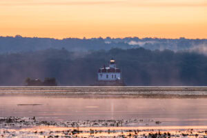 A photo of mist drifting off of the Hudson River during sunrise over the Esopus Lighthouse.