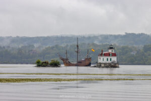 A photo of the Nao Trinidad, a 16th century tall ship replica, as it passes the Esopus Lighthouse as it travels up the Hudson River.